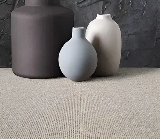 Bellaire neutral ribbed wool carpet with ceramic vases against a dark textured wall